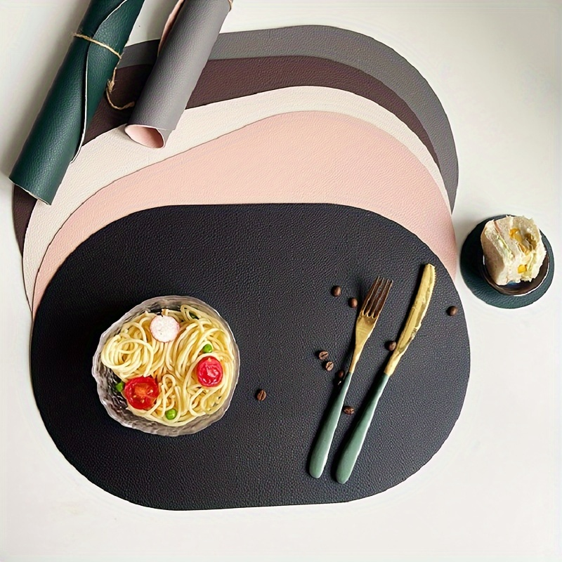 Four-piece set of oval faux leather placemats, reversible, heat resistant.
