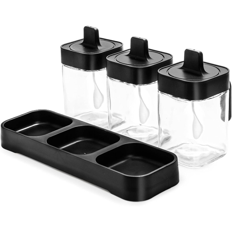 A set of three glass and wooden spice jars, with lids and spoons.