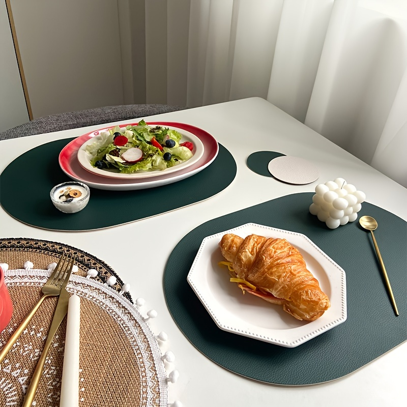 Four-piece set of oval faux leather placemats, reversible, heat resistant.